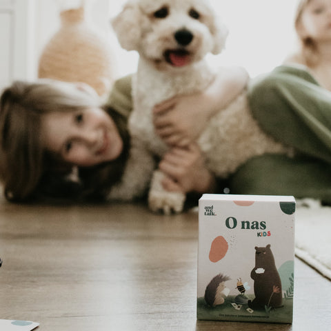 Une boîte de jeu au premier plan, et en arrière-plan un enfant souriant et un chien sur le sol