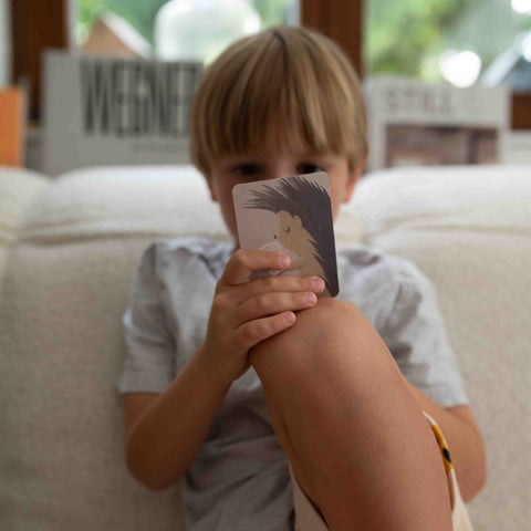 Un garçon tient devant son visage une carte du jeu pour enfants