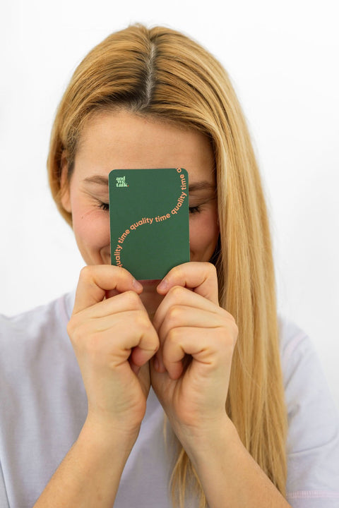 Une femme tient une carte Quality Time contre son visage