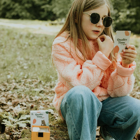 Une fille dehors avec une carte Quality Time Kids